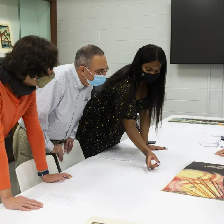 People looking at a work of art on a table.